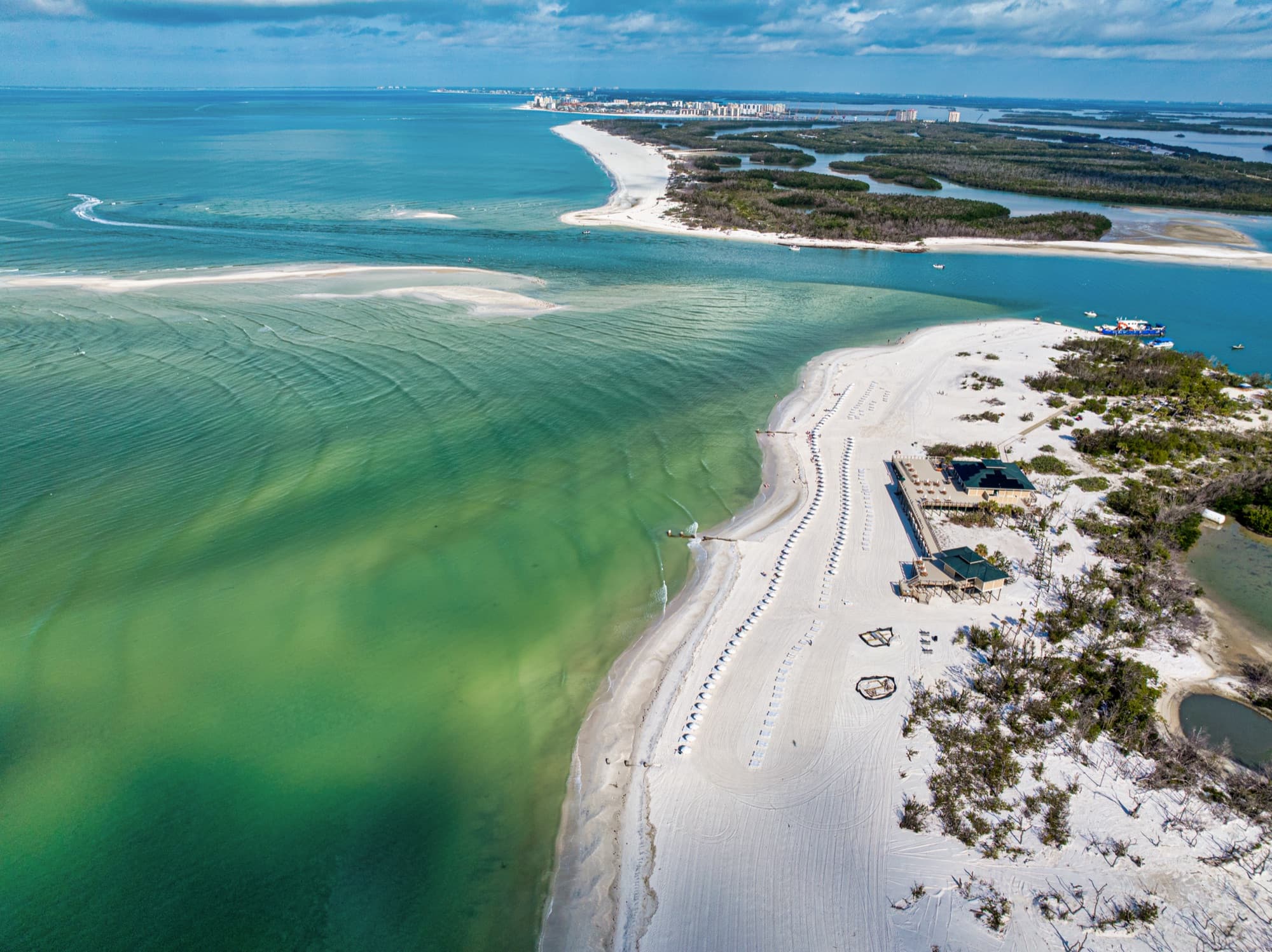 Aerial view of The Colony's private beach island with white sand and emerald Gulf water